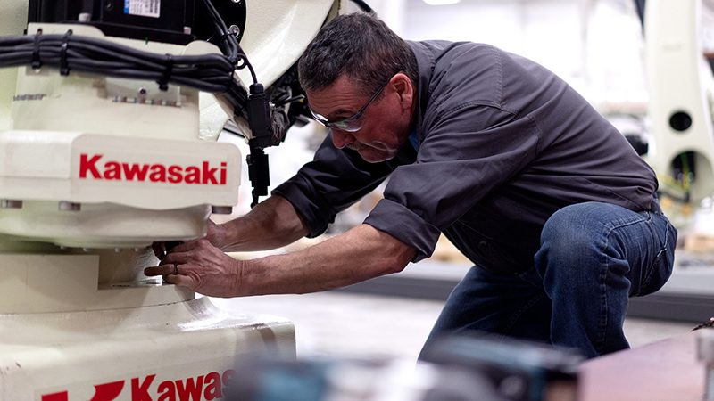 Kawasaki Customer Service team member works on a robot.