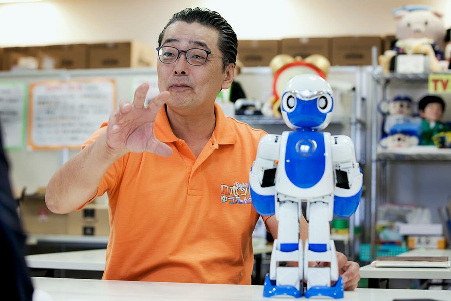 岡本氏がヒューマノイドのおもちゃを持って語っている様子